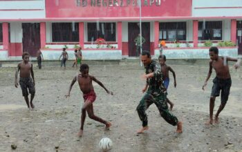 Personel Satgas TMMD Bermain Sepak Bola Bersama Anak-anak Meski Diguyur Hujan